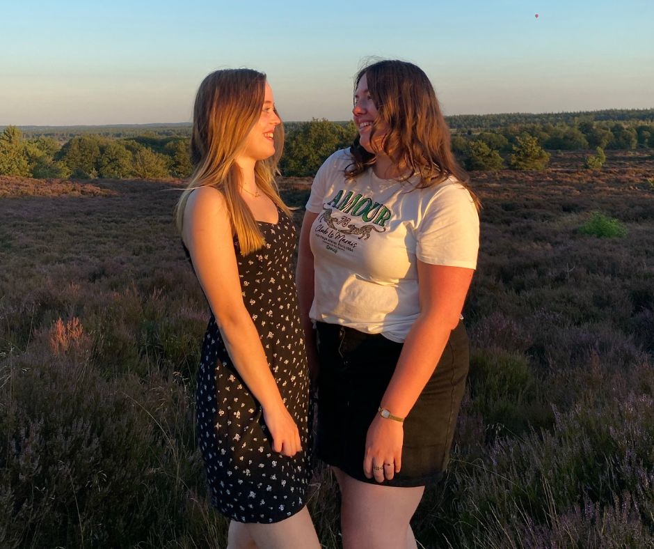 Two adolescent girls standing outside smiling at each other, teen reproductive health